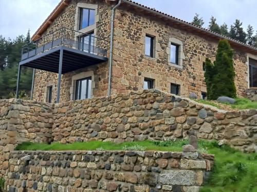 une maison en pierre avec un balcon au-dessus d'un mur en pierre dans l'établissement La Clef des songes, à Chazeaux