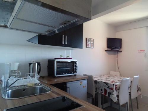 Il comprend une cuisine équipée d'un évier et d'une table avec un four micro-ondes. dans l'établissement Studio cosy 4 pers, ski aux pieds, casier à skis, parkings gratuits, équipement complet inclus. - FR-1-602-4, à Arette