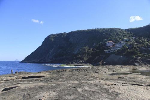 a group of people standing on a beach near the ocean at Hostel vila nova in Niterói