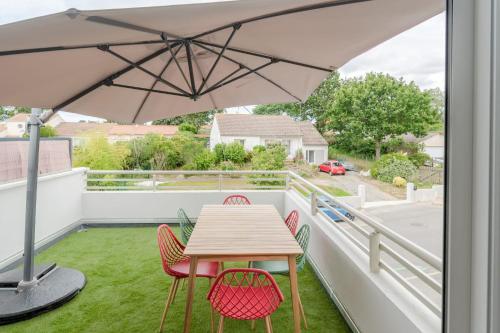 a table and chairs on a balcony with an umbrella at Maison aux Moutiers - Wifi - Terrasse in Prigny