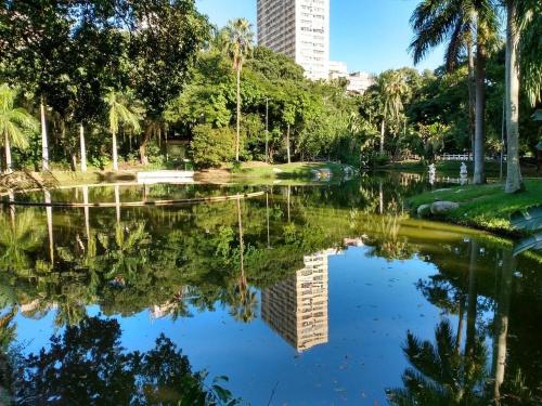 a pond in a park with palm trees and a tall building at Hostel vila nova in Niterói