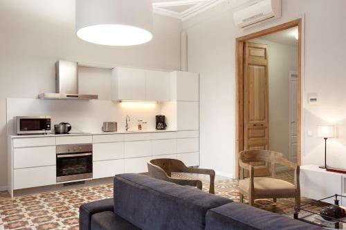 a living room with a blue couch and a kitchen at Rent Top Apartments Rambla Catalunya in Barcelona