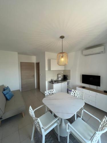 a living room with a white table and chairs at Apartmani Jakovinović in Ražanac