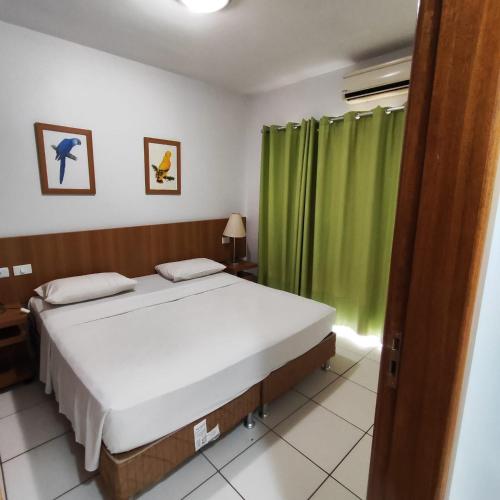 a bedroom with a bed and a green curtain at Golden Dolphin Grand Hotel piscinas 24 hs MP in Caldas Novas