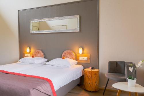 a bedroom with a bed with a mirror and a chair at Landhotel Diever in Diever