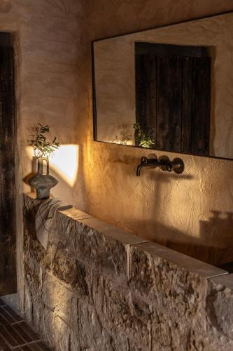 a stone wall with a mirror and a sink at Amalen Suites Adults Only in Rethymno Town