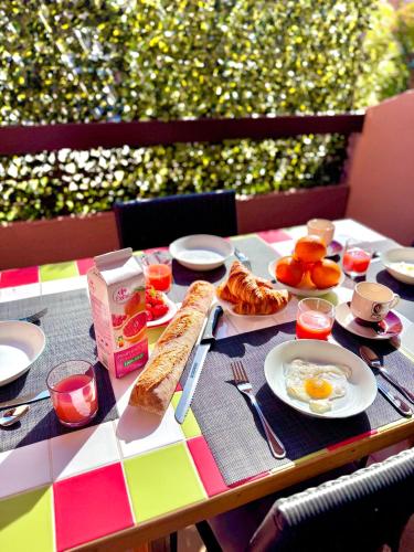 - une table avec des aliments pour le petit-déjeuner sur un tissu de table coloré dans l'établissement Le Lavandou Le Saint Clair, a deux pas de la plage de St Clair, au calme, Studio tout équipé, clim, Wifi Fibre, TV connectée, lave linge, lave vaisselle, place de parking et plus, serviettes et draps fournis, au Lavandou