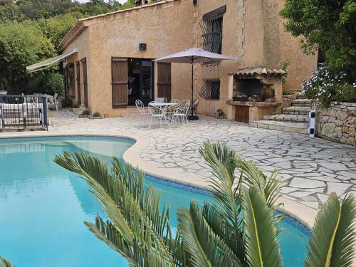 une maison avec une piscine et une table avec un parasol dans l'établissement Villa méditerranéenne 8 pers avec piscine aux Issambres - FR-1-768-112, à Saint-Peïre-sur-Mer