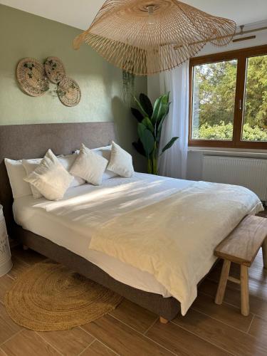 une chambre avec un grand lit blanc avec une fenêtre dans l'établissement L'Ecrin du Parc By Villa Gaïa - Terrasse et parc en centre ville, proche Eurexpo - Groupama - LDLC Arena - Aéroport, à Genas