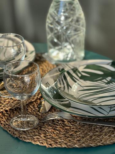 une table avec des assiettes et des verres sur une table dans l'établissement L'Ecrin du Parc By Villa Gaïa - Terrasse et parc en centre ville, proche Eurexpo - Groupama - LDLC Arena - Aéroport, à Genas