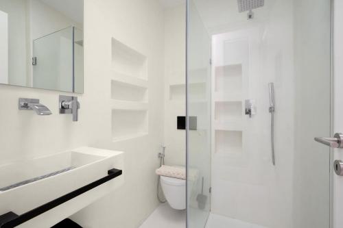 a white bathroom with a toilet and a glass shower at Sophisticated Paros Getaway in Parikia