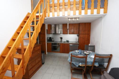 une cuisine avec un escalier en bois et une table et une cuisine avec une salle à manger dans l'établissement St Cyprien plage Maison avec terrasse et 2 velos, à Saint-Cyprien
