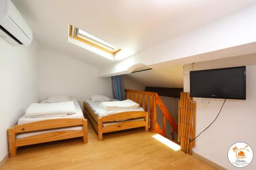 une chambre avec deux lits et une télévision à écran plat dans l'établissement St Cyprien plage Maison avec terrasse et 2 velos, à Saint-Cyprien