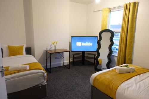 ein Zimmer mit zwei Betten und einem Flachbildfernseher in der Unterkunft Kyoto Central I 4 BDR House I 50 inch Smart TVs in Rooms I Large Spacious Rooms I Refurbished I Derby City Centre in Derby