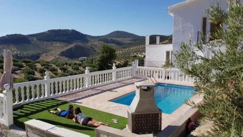 a group of people laying on the grass by a swimming pool at Elegant House with Pool in Alcaudete in Sabariego