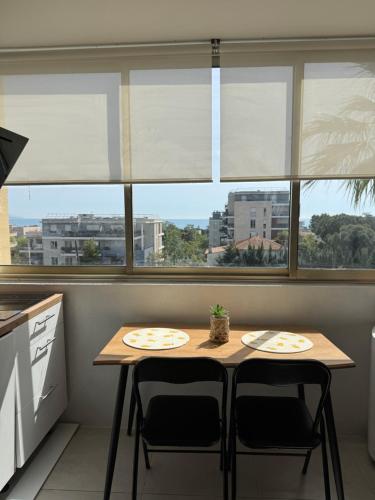 une table et des chaises dans une cuisine avec fenêtres dans l'établissement Studio Cosy vue mer, à Antibes