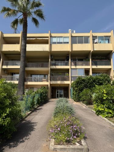 un immeuble d'appartements avec un palmier et une allée dans l'établissement Studio Cosy vue mer, à Antibes