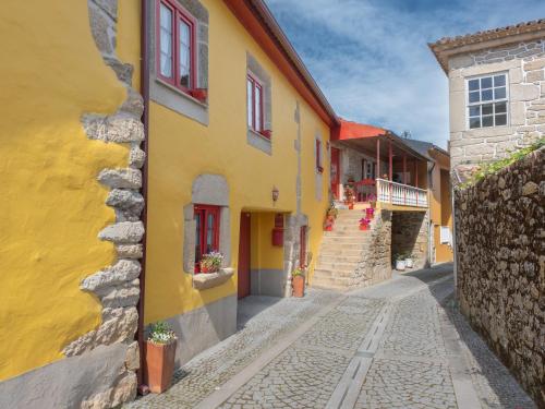 a yellow building with red windows on a street at Casa do Sino, Estadia Moderna Perto do Douro in Tarouca