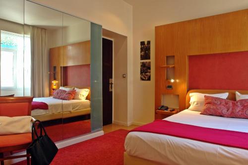 アテネにあるセメリ ホテルのベッド2台と鏡が備わるホテルルームです。