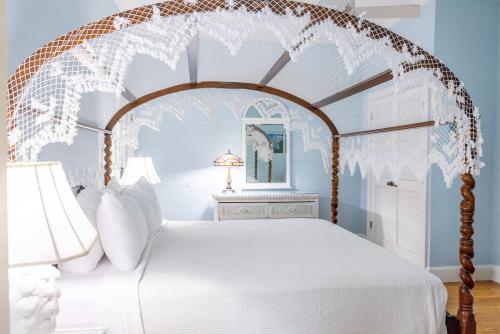 a bedroom with an ornate canopy bed with white pillows at Deluxe King with Balcony - at James House with Parking! in Key West