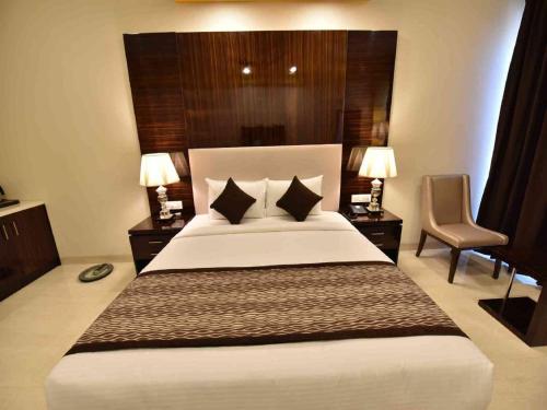 a bedroom with a large white bed with two tables and a chair at Hotel Calangute Central in Calangute