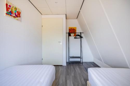 two beds in a room with white walls at Kramsvogel I Woning met Fijne Tuin in Zwiggelte