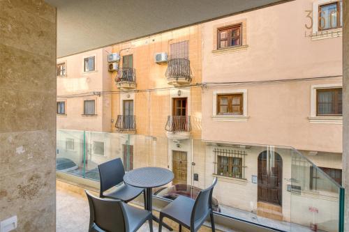 Un balcón con una mesa y sillas y un edificio. en Rooftop Pool Sensations Apartments all with WIFI and AC by 360 Estates, en Mellieħa