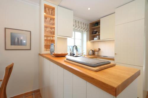a kitchen with white cabinets and a wooden counter top at Haus Munkhoog in Munkmarsch