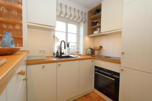 a kitchen with white cabinets and a black dishwasher at Haus Munkhoog in Munkmarsch