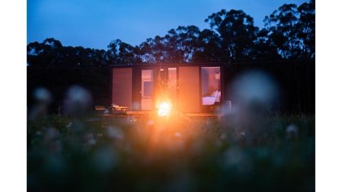 a person is sitting in a tiny house at night at Gumnut by Tiny Away in Kangaroo Valley