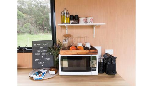 a microwave oven with a cutting board on top of it at Gumnut by Tiny Away in Kangaroo Valley