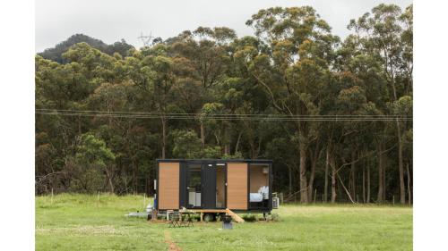 a tiny house in a field with trees in the background at Gumnut by Tiny Away in Kangaroo Valley
