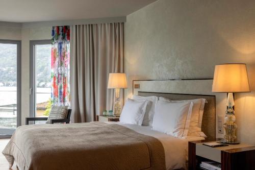 a hotel room with a large bed with two lamps at Hotel Eden Roc - The Leading Hotels of the World in Ascona