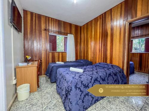 two beds in a room with wooden walls at Hotel Fazenda Golden Park Campos do Jordão in Campos do Jordão