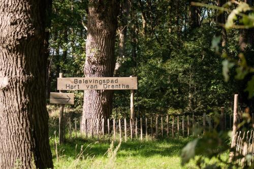 a sign that reads bellingswick half way deficit next to trees at Kramsvogel I Woning met Fijne Tuin in Zwiggelte