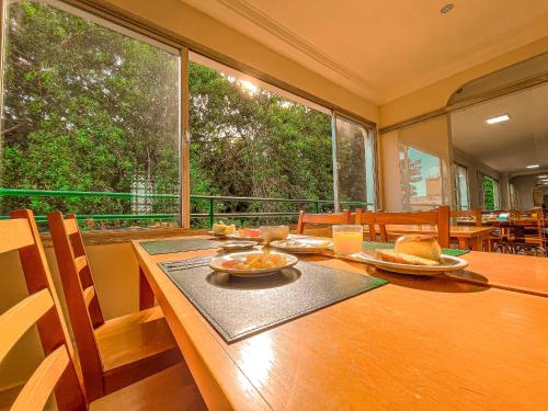 a dining room with a table and a large window at Hotel Nacional Inn Guarujá in Guarujá
