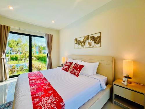 a bedroom with a bed with red pillows and a window at Relax Pool Villa Khaoyai - รีแล็กซ์พูลวิลล่าเขาใหญ่ in Ban Bung Toei