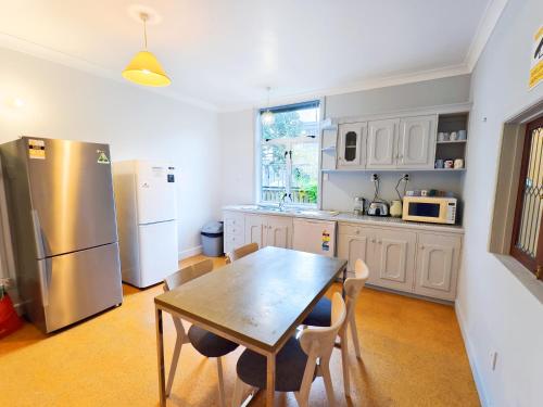 a kitchen with a table and a stainless steel refrigerator at Parakai Geothermal Motel in Parakai