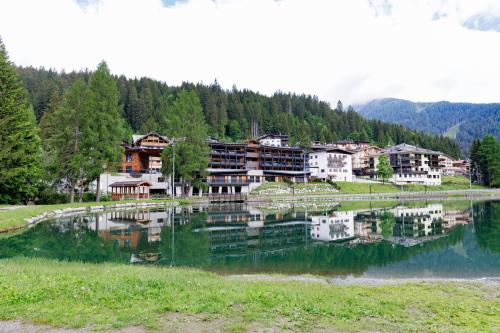 a group of buildings next to a lake at Campiglio WOOD in Madonna di Campiglio