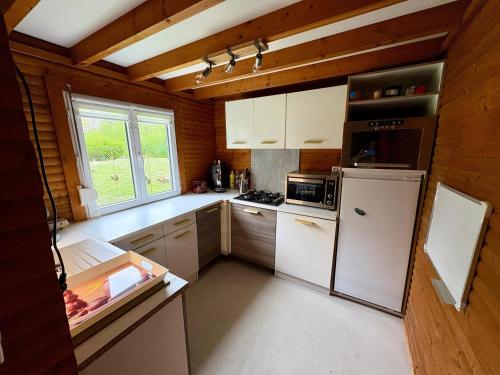a kitchen with a white refrigerator and a window at Chalet convivial avec vue sur la rivière - 62 m² in Authuille