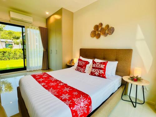 a bedroom with a bed with red pillows and a window at Relax Pool Villa Khaoyai - รีแล็กซ์พูลวิลล่าเขาใหญ่ in Ban Bung Toei