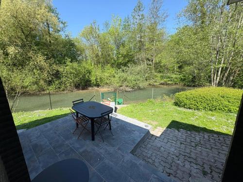 a patio with a table and a view of a river at Chalet convivial avec vue sur la rivière - 62 m² in Authuille