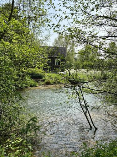a house in the middle of a river with a building at Chalet convivial avec vue sur la rivière - 62 m² in Authuille
