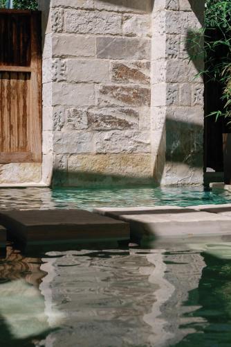 a pool of water next to a stone building at Amalen Suites Adults Only in Rethymno Town
