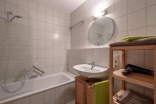Un baño con lavabo, bañera y espejo. en Ferienwohnung Ella, en Meersburg
