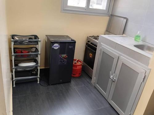 Una cocina con un refrigerador negro y un fregadero. en Appartement Beau Séjour, en Dakar