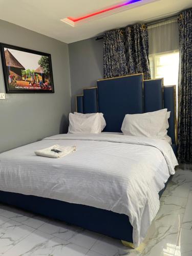 a large bed with a blue headboard in a bedroom at Umbrella Properties hotels and apartments - Moniya in Ibadan