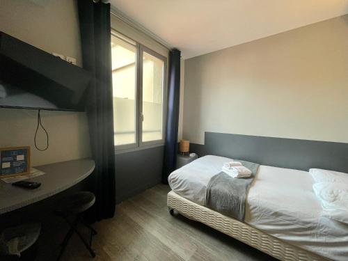 a bedroom with a bed and a desk and a window at Hôtel De Paris in Sète