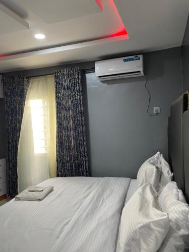 a bedroom with a white bed and a window at Umbrella Properties hotels and apartments - Moniya in Ibadan