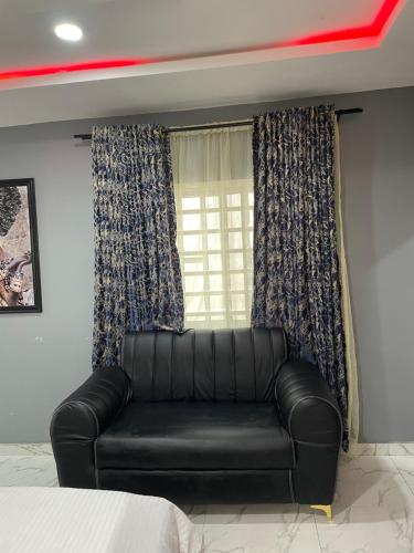 a black leather couch in a room with a window at Umbrella Properties hotels and apartments - Moniya in Ibadan